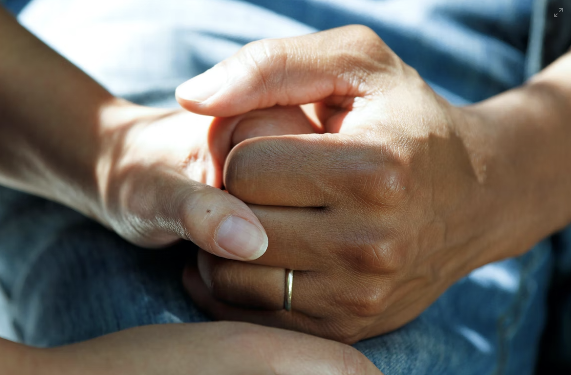 Two people holding hands on blue background.