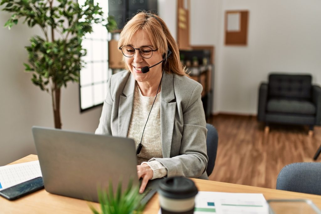 A middle-aged business women who is working for a senior care advisor franchise in her home office.